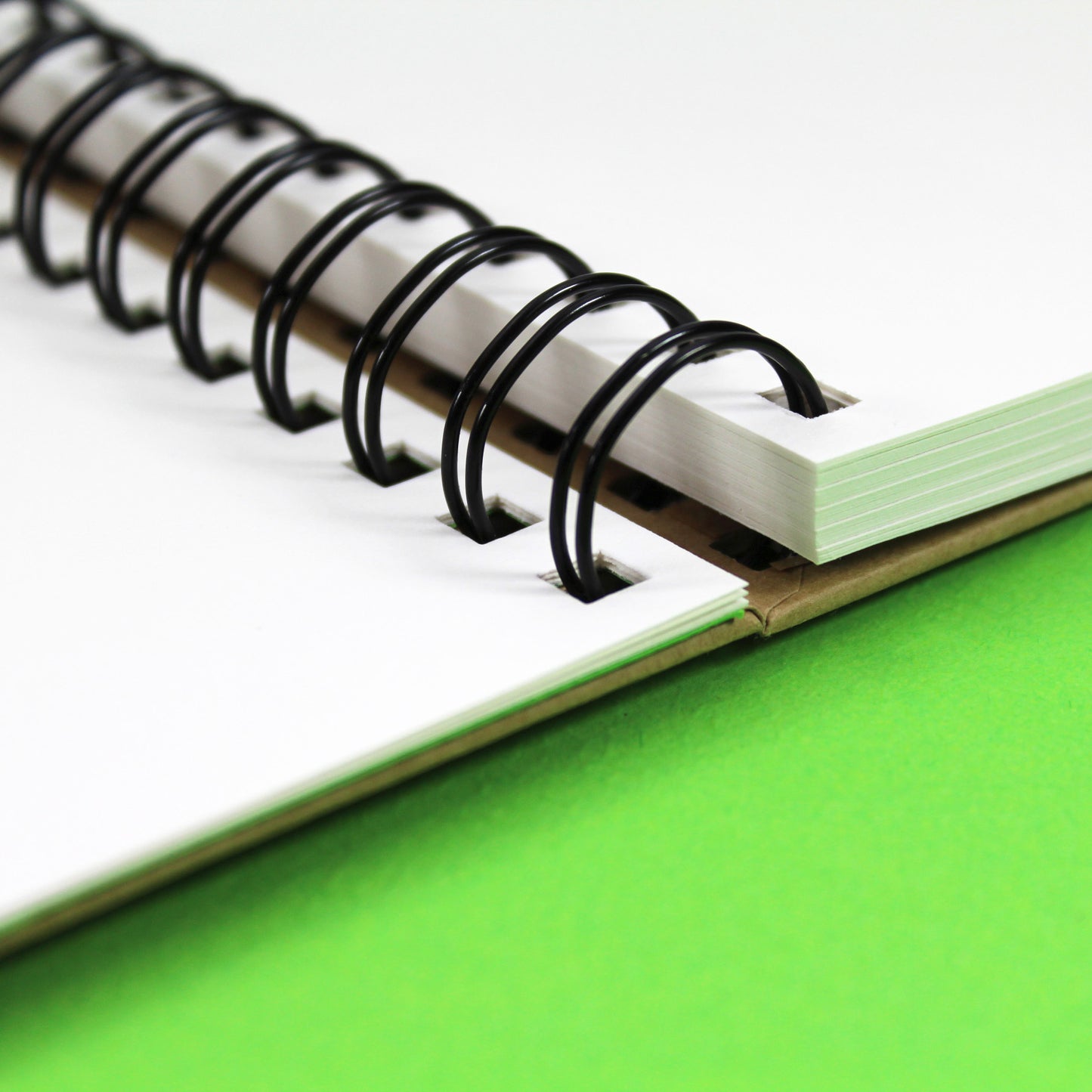 Close up of a 'Krafty' Gecko sketchbook that is open to reveal the white cartridge paper inside and twin wire binding.