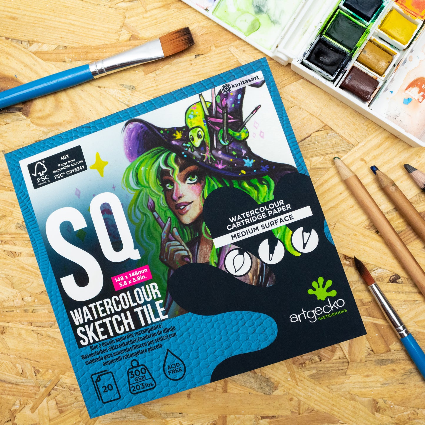 Artgecko watercolour sketch tile packaging on a wooden surface with art supplies.