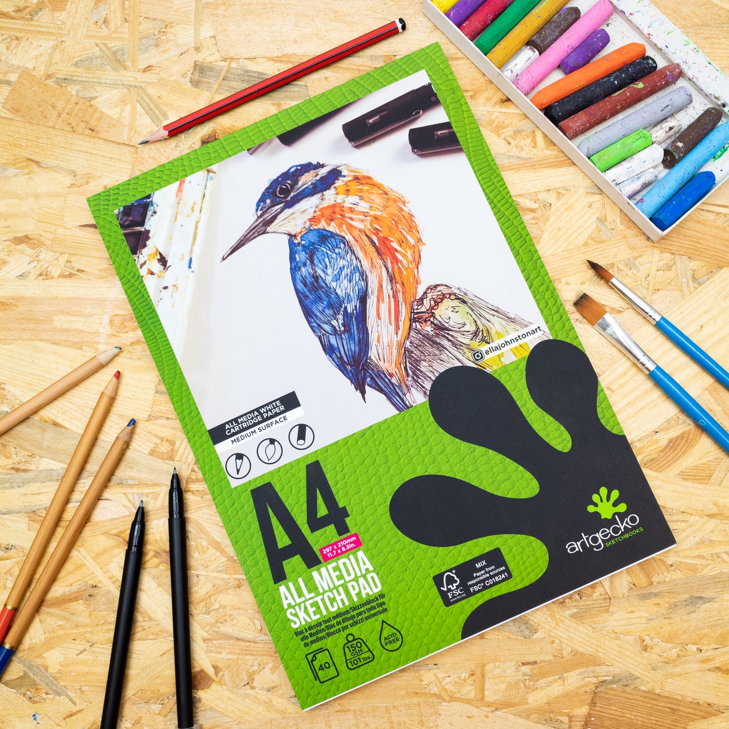 A4 Artgecko sketch pad with art supplies on a wooden surface