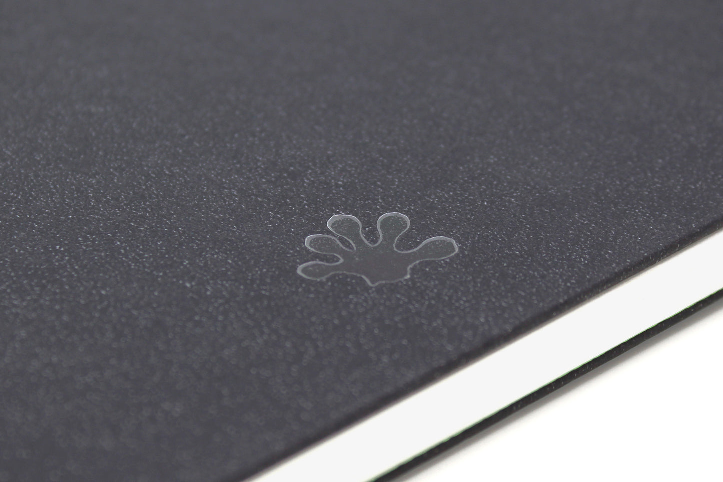 Close-up of the black cover of a Classy All Media Sketchbook. This is of the bottom of the back cover where the iconic gecko footprint stamp of approval appears.